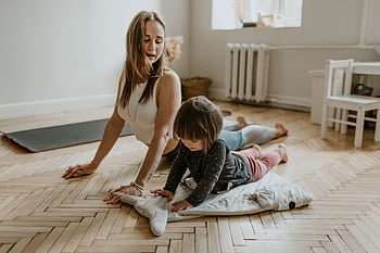 A mother and child practicing yoga together at home on a sunny day, fostering wellness and connection. HD wallpaper