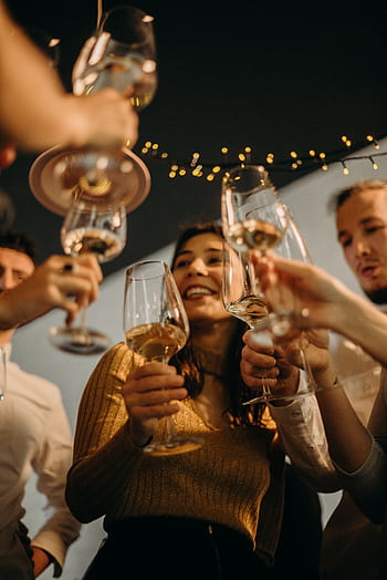 Friends celebrating with a wine toast at an indoor night party, cheerful atmosphere. HD phone wallpaper