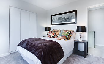 Stylish and contemporary bedroom featuring a cityscape artwork, colorful pillows, and modern decor. HD wallpaper