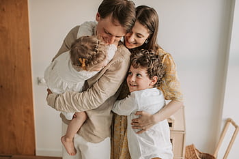 A heartwarming scene of a family hugging indoors, showcasing love and togetherness. HD wallpaper
