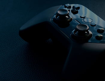 A detailed macro shot of a black game controller with reflections, emphasizing technology and gaming. HD wallpaper