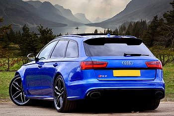 A sleek blue Audi RS 6 wagon parked against a stunning backdrop of Scottish hills and a serene lake. HD wallpaper