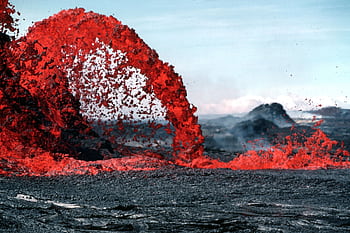 Stunning of vibrant red lava flowing during a volcanic eruption in a rugged landscape. HD wallpaper