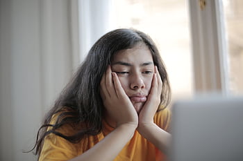 A woman ponders while browsing online, capturing a contemplative and introspective moment. HD wallpaper