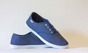 Pair of stylish blue canvas shoes with white soles displayed against a neutral background. HD wallpaper