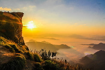 Breathtaking view of sunrise with mist and green cliffs, capturing nature's beauty. HD wallpaper