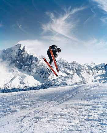 Dynamic ski jump in stunning snowy mountain landscape, epitomizing winter sports excitement. HD phone wallpaper