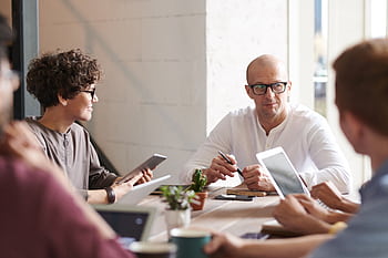 Group of professionals engaged in a brainstorming session around a table in a contemporary office space. HD wallpaper