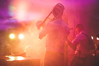 Vibrant live music performance featuring a trombone player on stage in a nightclub setting. HD wallpaper
