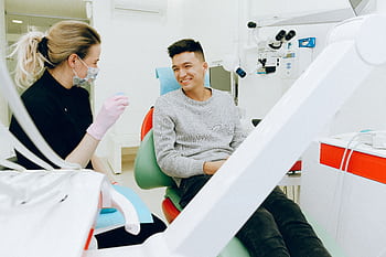 A dentist and patient smiling during a dental checkup, showcasing friendly healthcare interaction indoors. HD wallpaper