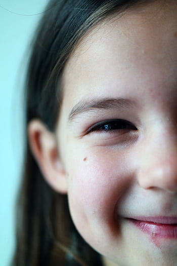 Delightful close-up of a young girl smiling, evoking happiness and innocence. HD phone wallpaper