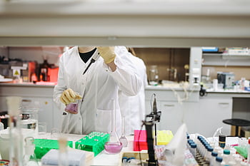 Scientist in a lab coat handling samples for scientific research in a modern laboratory setting. HD wallpaper