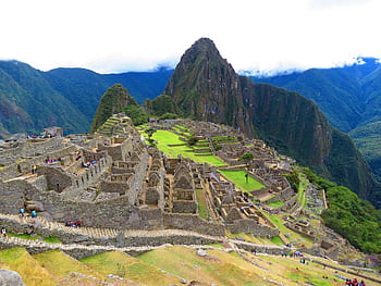 Stunning aerial perspective of Machu Picchu with lush surroundings under a cloudy sky. HD wallpaper