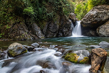 Tranquil waterfall cascading through mossy rocks in a lush forest setting. Perfect for nature lovers. HD wallpaper