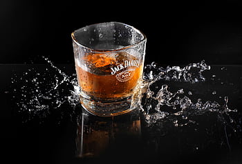 Dynamic shot of whiskey with ice and splash, highlighting Jack Daniel's brand on glass. HD wallpaper