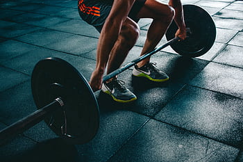 Man performing a deadlift exercise in a gym, demonstrating strength and fitness. HD wallpaper