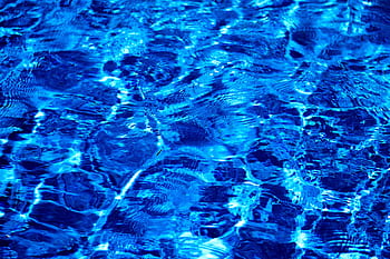 Dynamic and vibrant ripples on a blue water surface, showcasing light and texture. HD wallpaper