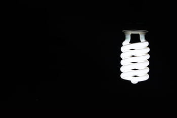 Bright spiral LED lightbulb against black background, artistic minimalism. HD wallpaper