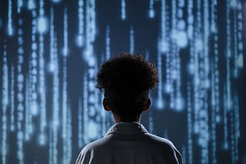 A young boy viewing a digital screen with data streams, symbolizing technology interaction. HD wallpaper