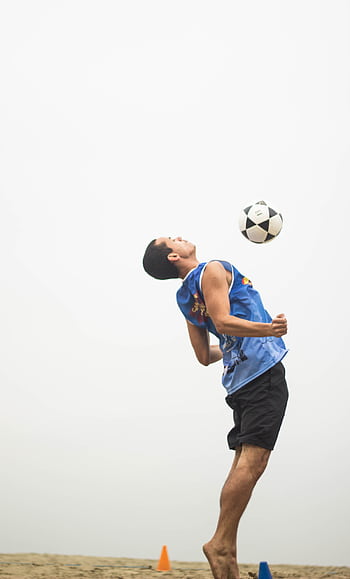 A young man dynamically performs a soccer trick outdoors, emphasizing speed and agility. HD phone wallpaper
