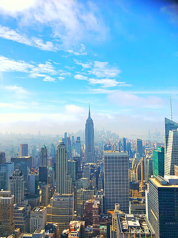A breathtaking view of the New York City skyline featuring the iconic Empire State Building under a bright blue sky. HD phone wallpaper