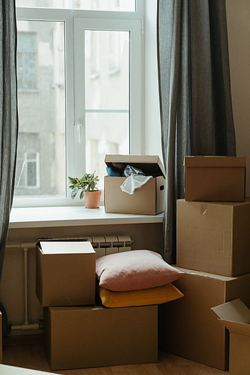 Stack of moving boxes in a sunlit room, symbolizing a fresh start in a new apartment. HD phone wallpaper