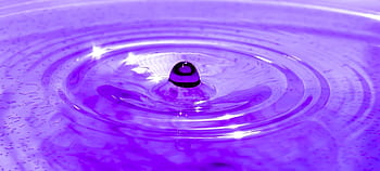 Captivating macro of a droplet creating ripples on a purple liquid surface. HD wallpaper