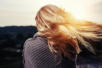 Back view of a woman with blonde hair blowing in the wind during sunset outdoors. HD wallpaper