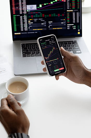 Person analyzing stock market trends on smart with laptop background HD phone wallpaper
