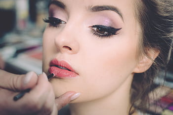 A close-up portrait of a woman getting professional makeup applied indoors, highlighting elegance and beauty. HD wallpaper