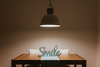 Stylish interior featuring a wooden table, modern lamp, and 'Smile' decor for a warm ambiance. HD wallpaper