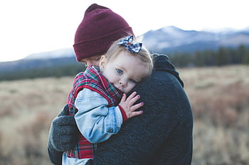 A father and child embrace outdoors with a winter mountain backdrop. HD wallpaper