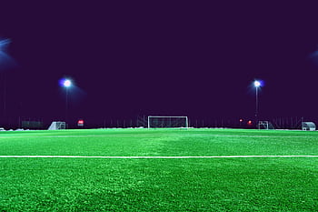 A brightly lit soccer field at night in Norrtälje, Sweden, showcasing green turf and stadium lights. HD wallpaper