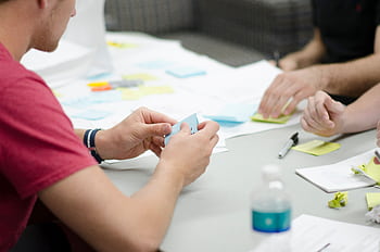 Collaborative workspace with people brainstorming using sticky notes, emphasizing teamwork and planning. HD wallpaper