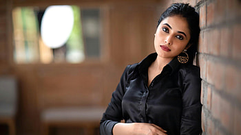 Actress Priyanka Arul Mohan Girl Model Is Leaning Back On Brick Wall Standing In Blur Background Wearing Black Dress Girls HD wallpaper