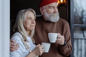 A senior couple embraces while enjoying coffee, symbolizing love and companionship. HD wallpaper