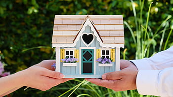 Close-up of hands holding a detailed miniature house model, symbolizing goals of homeownership. HD wallpaper
