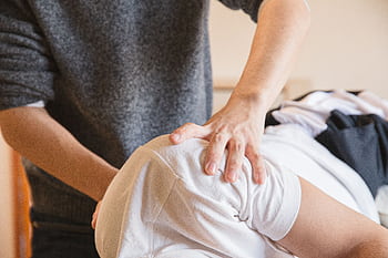 Close-up of a chiropractor performing shoulder therapy on a patient indoors. HD wallpaper