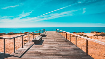 Idyllic boardwalk leading to the ocean with clear skies and calm sea. HD wallpaper