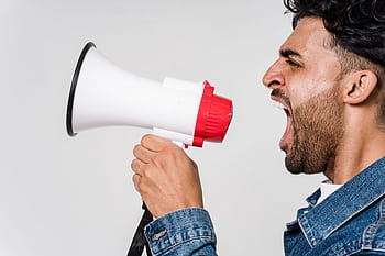Close-up side view of a man shouting passionately into a mega, expressing urgency. HD wallpaper