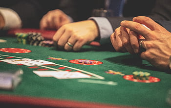 Hands playing blackjack in a casino setting with cards and chips on a green table. HD wallpaper