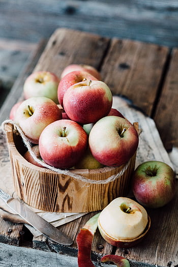 A close-up of ripe apples in a wooden basket on rustic planks. Ideal for fall harvest themes. HD phone wallpaper