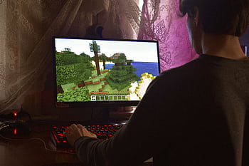 A young man intensely playing a PC video game indoors. Capturing the essence of technology and concentration. HD wallpaper