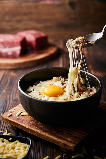 A delicious melted cheese and egg bowl on a wooden board with beef in the background. HD phone wallpaper