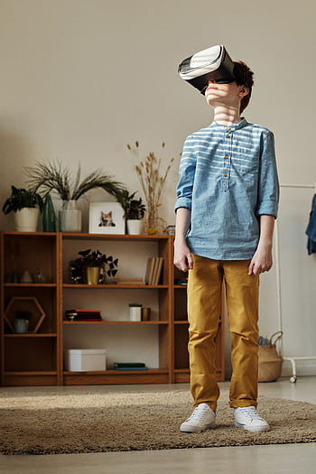 A young boy wearing VR goggles, exploring virtual reality in a cozy living room. HD phone wallpaper