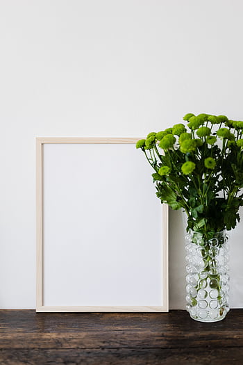 Elegant minimalist arrangement with green chrysanthemums in a vase beside a blank wooden frame. HD phone wallpaper