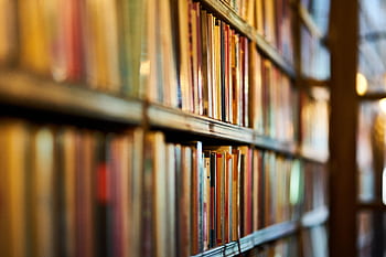 Close-up view of library shelves filled with books, ideal for concepts of education and literature. HD wallpaper