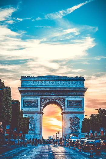 Capture of the Arc de Triomphe at sunset with bustling Paris street life. HD phone wallpaper