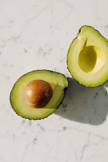 A minimalistic top view of a fresh halved avocado on a light marble background. HD phone wallpaper
