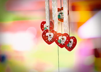 Vibrant heart-shaped decorations with love message hanging against a colorful blurred background. HD wallpaper